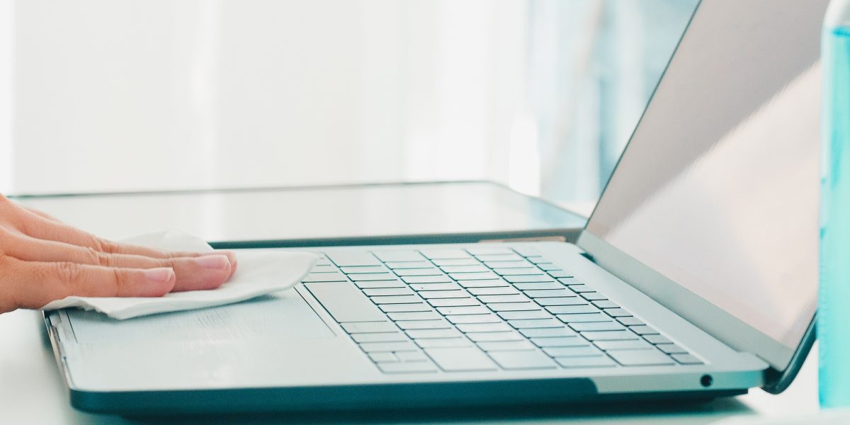Asian woman using alcohol spray on tissue clean laptop before open for protect coronavirus.
