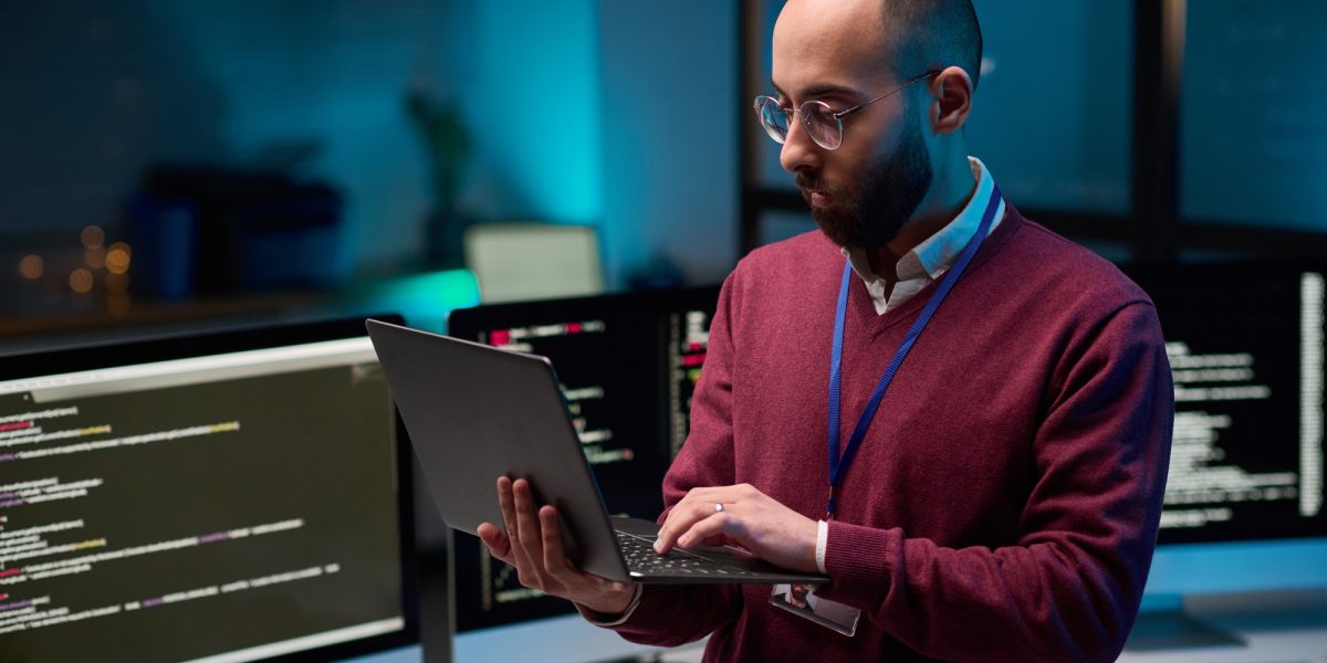 Bearded Man Holding Laptop in Cybersecurity Office