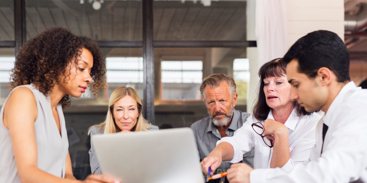 Business people using laptop at meeting in office