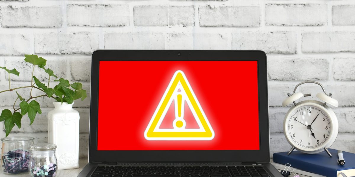 Computer screen showing red screen with yellow glowing danger sign. Concept hack virus cyber attack