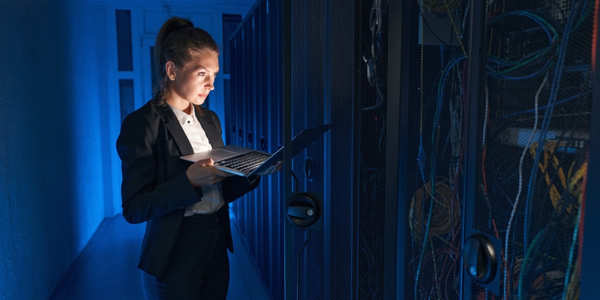 Confident system administrator working on laptop in data center