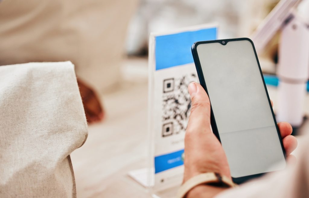 Hands, phone and store to scan qr code for payment, trading or cybersecurity with fintech, service