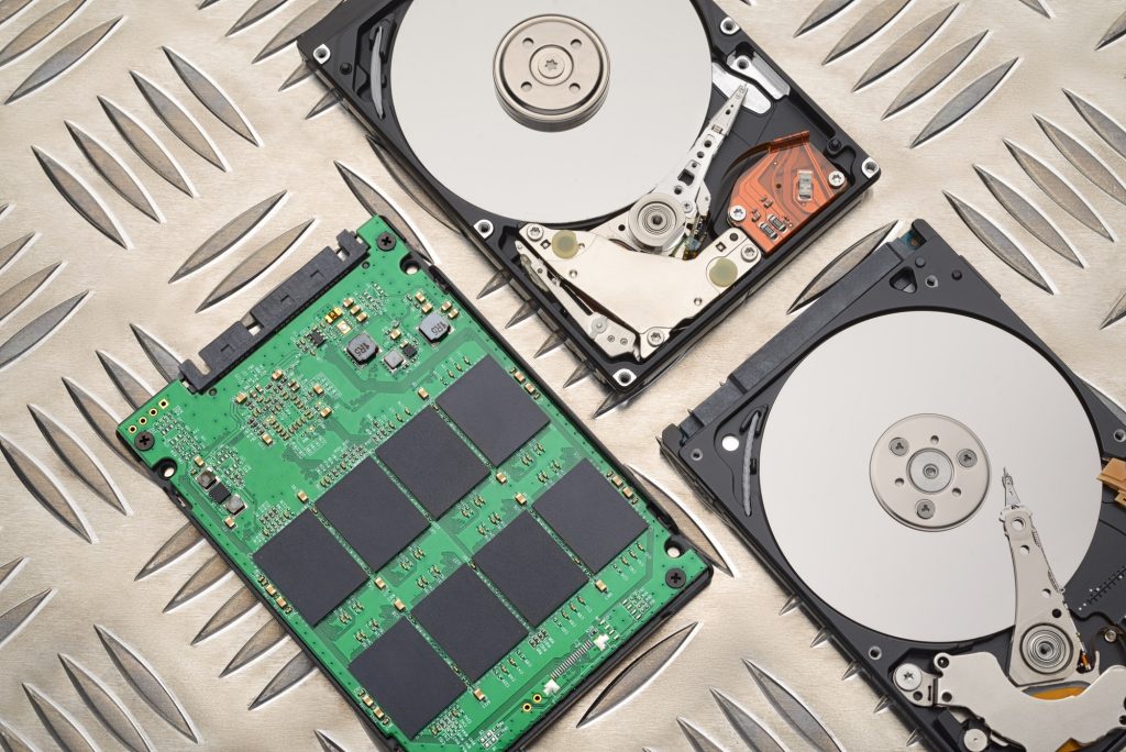 Open HDD and SSD disk drives on metal plate background