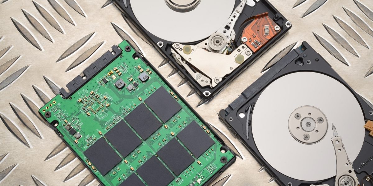 Open HDD and SSD disk drives on metal plate background