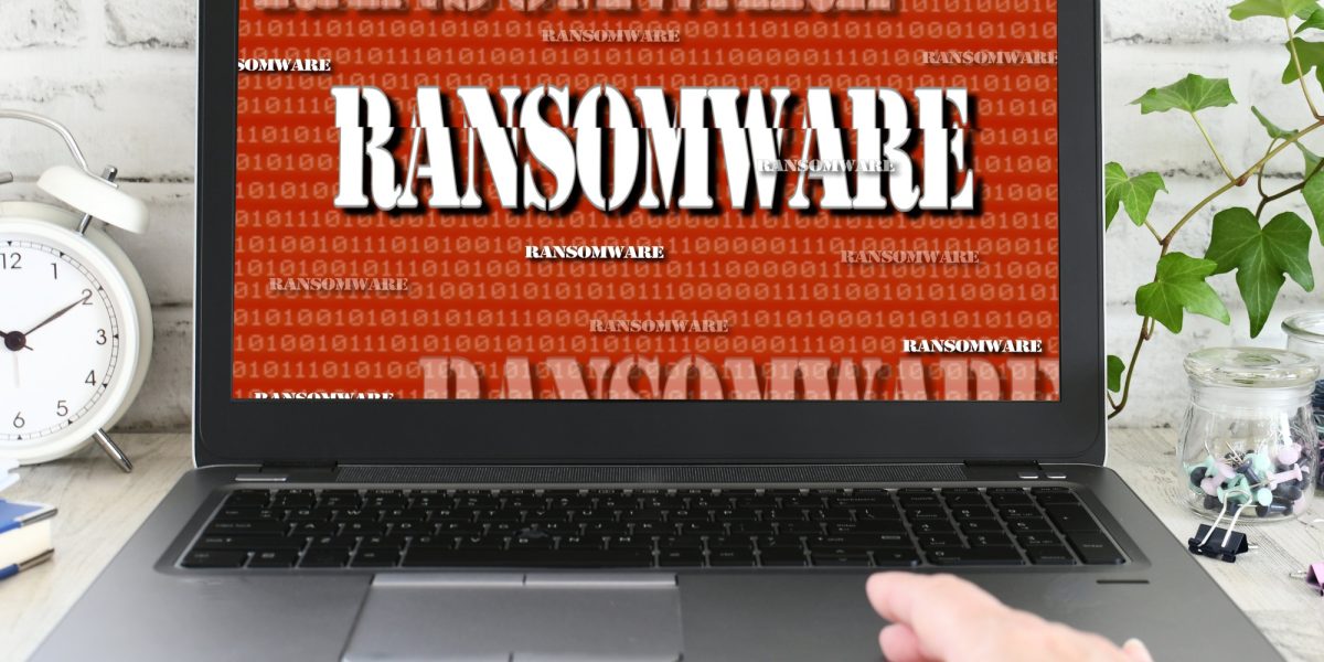 Person working on a laptop computer that has been seized by a ransomware cyber attack. hacked virus
