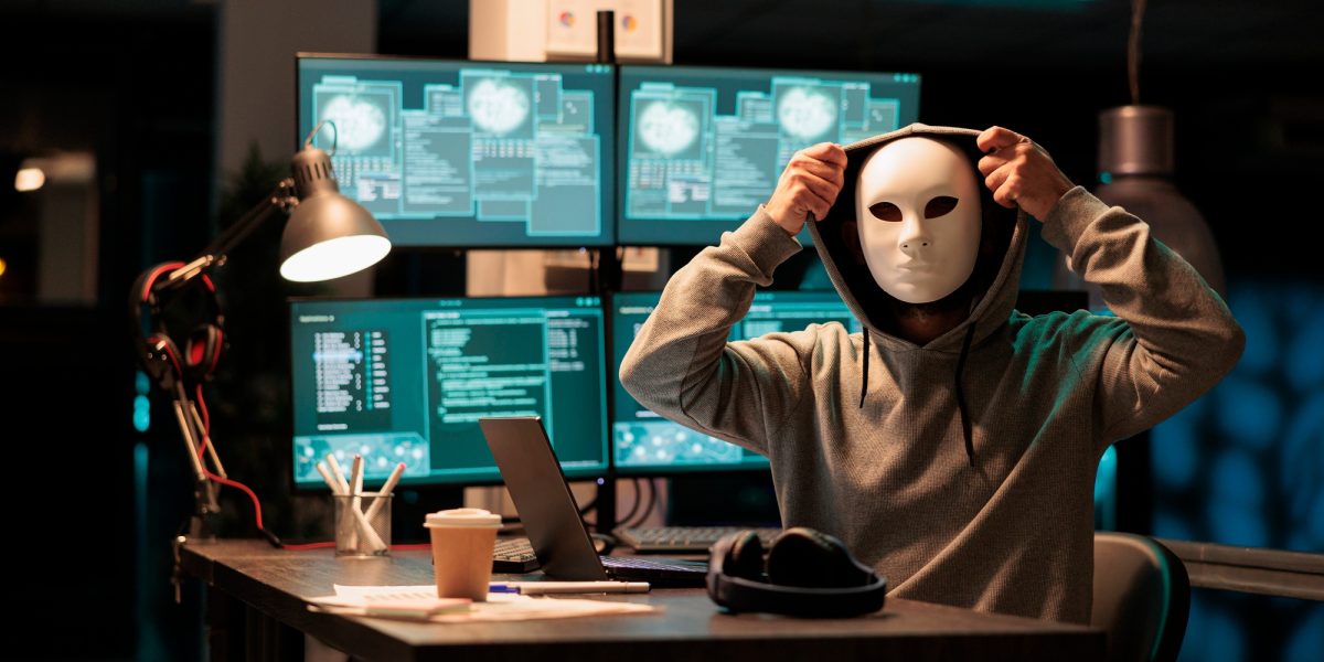Scary masked hacker installing virus to hack system
