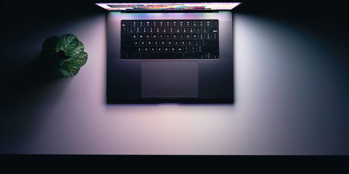 Top view of a laptop on a table, glowing screen in the dark.