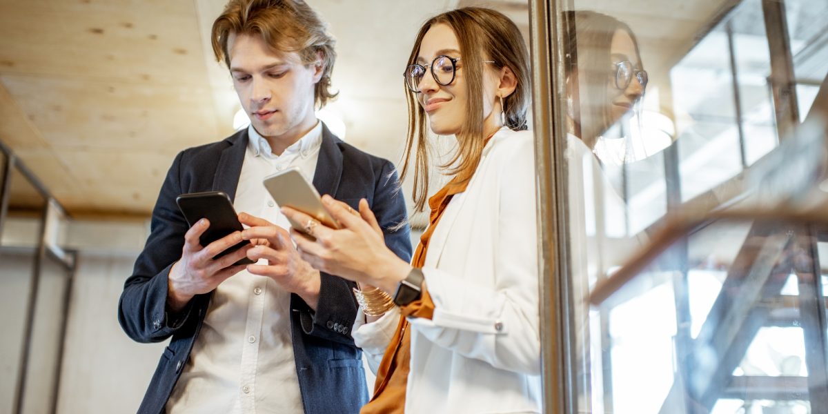 Business man and woman with smartphones in the office